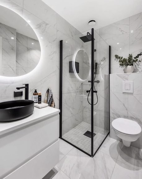 Compact marble effect en-suite with black framed corner shower