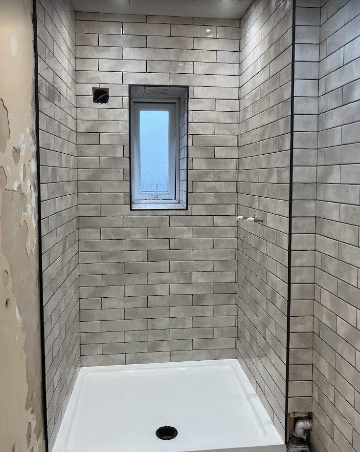 Shower enclosure part way through tiling with the window reveal cut in