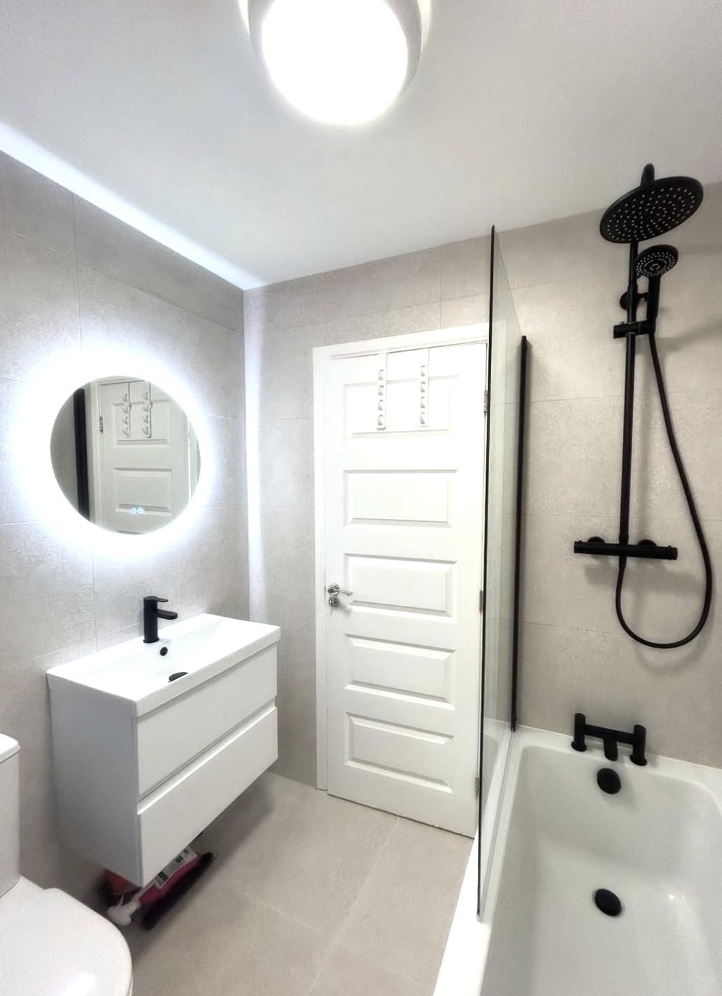 White bathroom with large format tiles and matt black shower over the bath